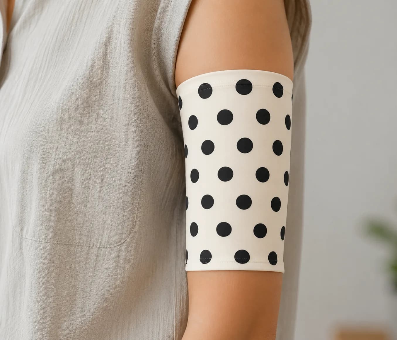 White PICC line cover with black polka dots, worn on the upper arm