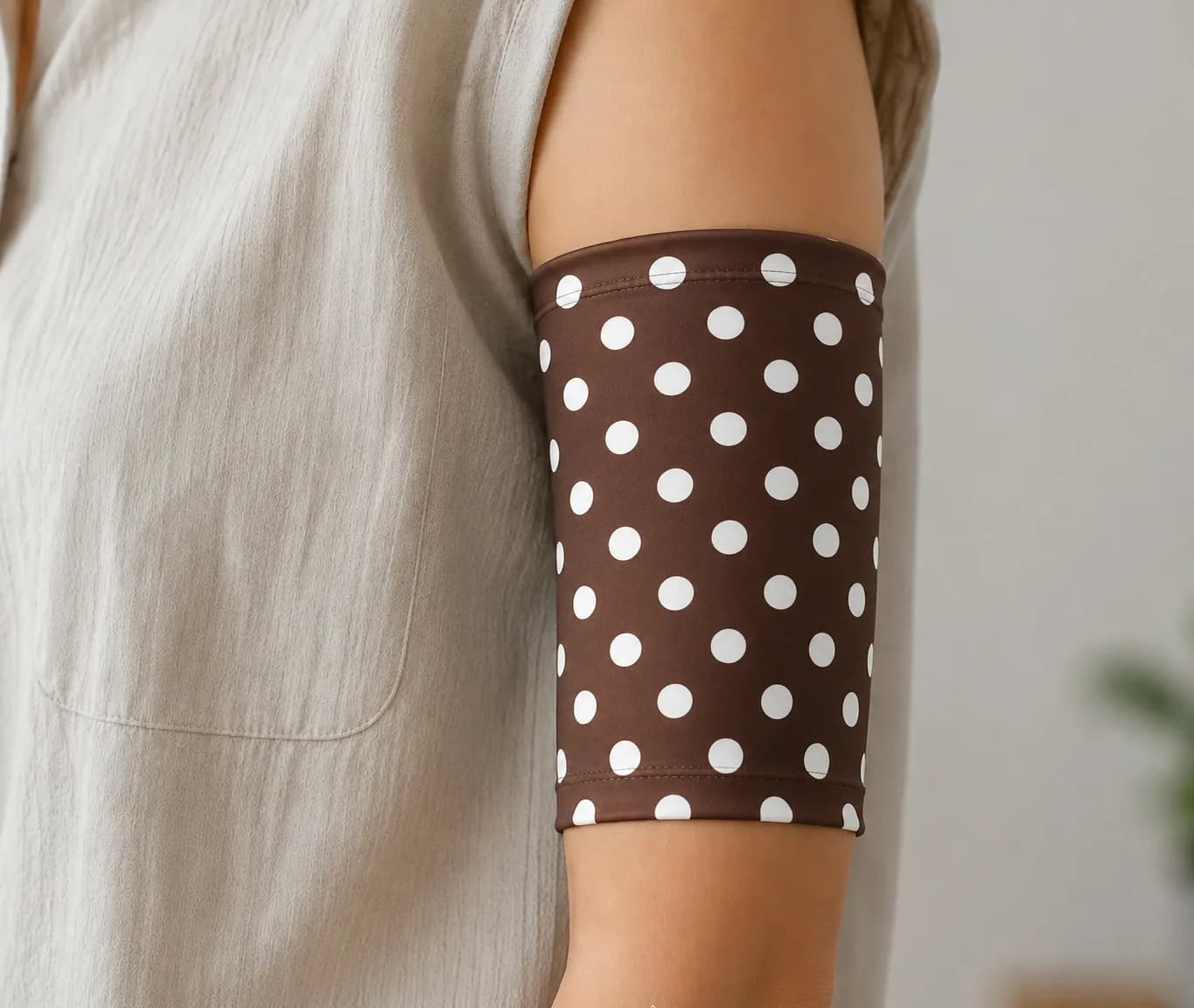 Brown PICC line cover with white polka dots, worn on the upper arm